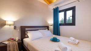 Quarto com cama, luminárias laterais, janela com cortinas e mesa de cabeceira com abajur e um livro.