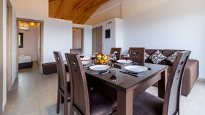 Uma sala de jantar com teto de madeira, mesa de vidro e cadeiras marrons.