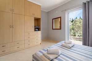 Quarto com cama, guarda-roupa, espelho e vista para a varanda.