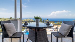 A balcony with wicker chairs, a glass table, and a potted plant. - 'Apartment with Sea View B' with Pool, Garden, Terrace & Wi-Fi (?e???da)
