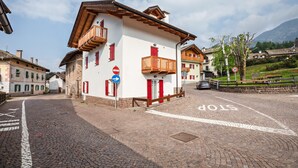 A cobblestone street with a stop sign, a building with a balcony, and a mountain in the background. - Holiday Apartment 'Le Coccinelle' with Mountain View, Terrace & Wi-Fi (Varena)