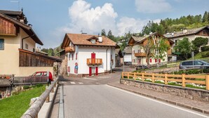 A street with traditional buildings, a clear sky, and a parked car. - Holiday Apartment 'Le Coccinelle' with Mountain View, Terrace & Wi-Fi (Varena)