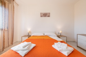 Une chambre d’hôtel avec un lit, deux tables de chevet, une petite table, une commode et un tableau au mur.