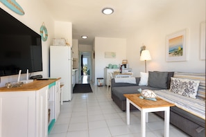 Um espaço compacto para viver, com cozinha compacta, sofá, mesa de centro e televisão.