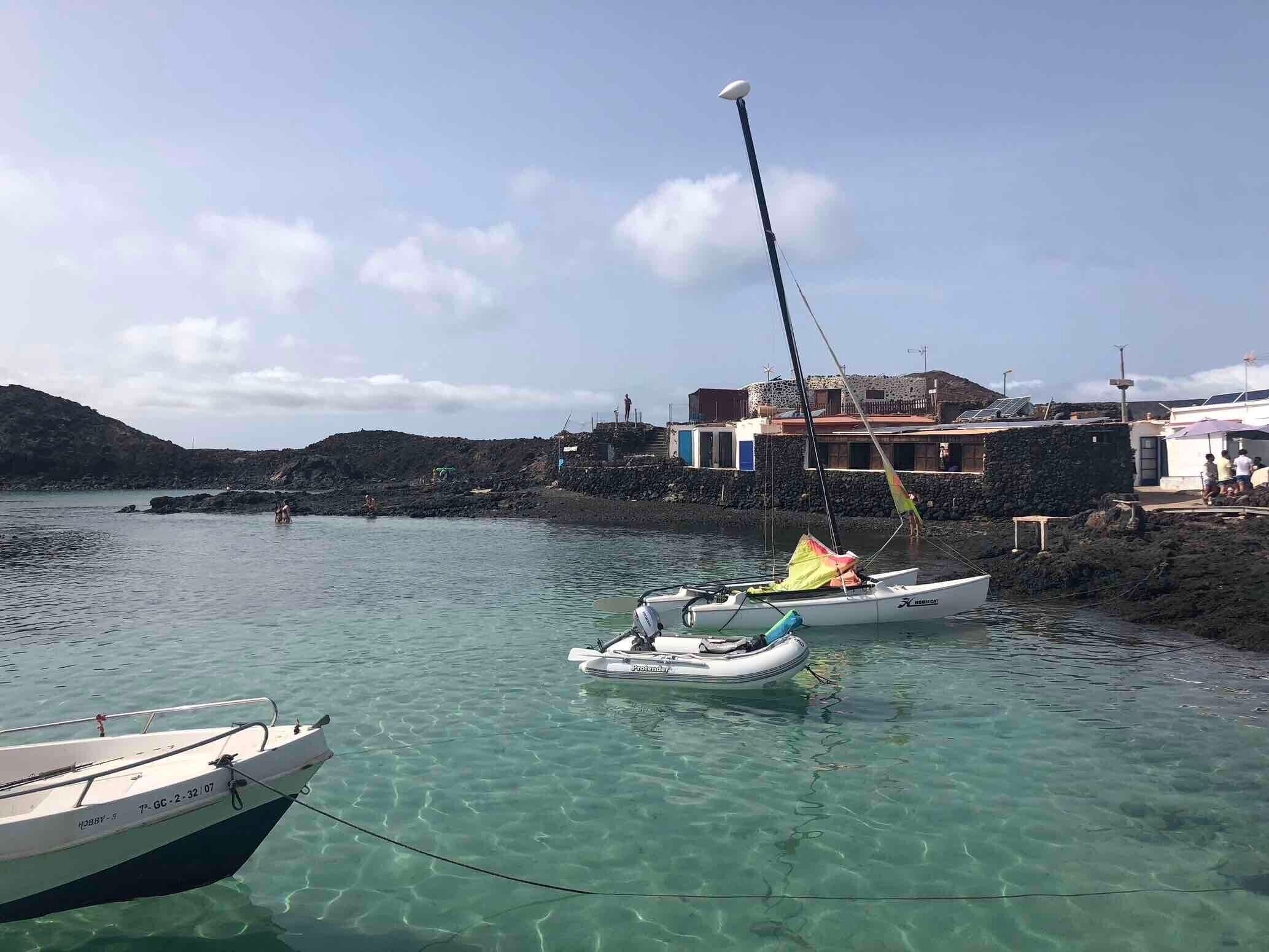 A coastal scene with boats, a clear sky, and buildings along the shore.