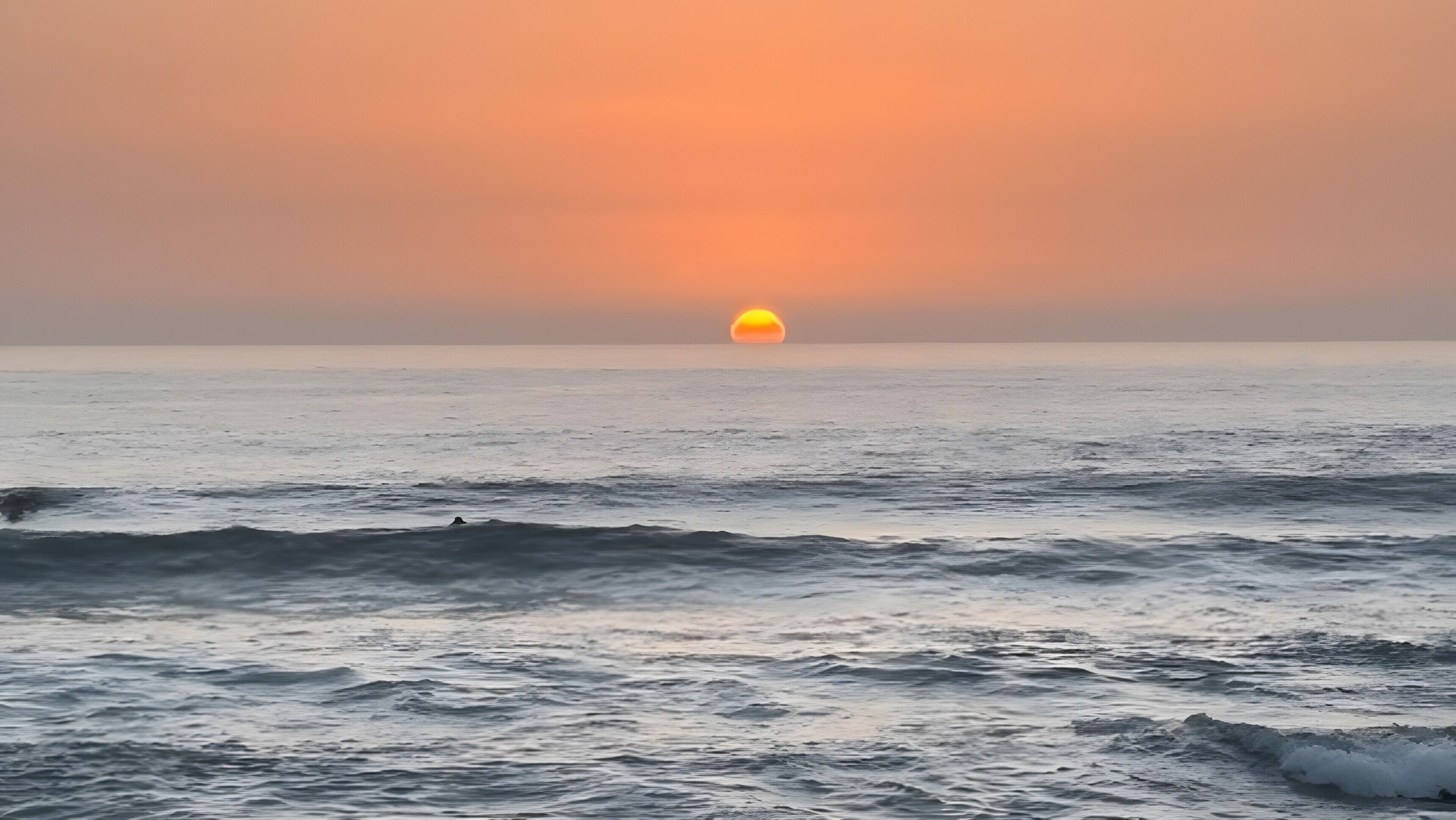 Un atardecer sobre el océano con olas.