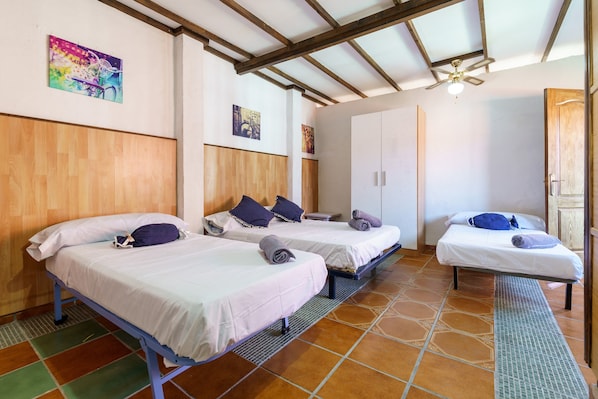 A room with two beds, a ceiling fan, and a door.