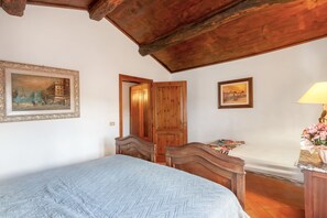 Un dormitorio con cama, armario de madera y escritorio con lámpara.