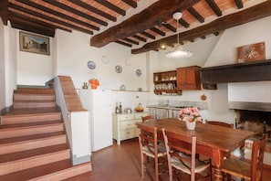 Une cuisine avec une table en bois, des chaises et une cheminée.