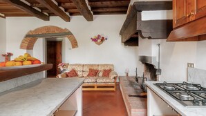 Una cocina con encimera de mármol, un banco de madera, chimenea de ladrillo y techo rústico.