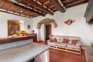 Una habitación con encimera de mármol, vigas de madera, un sofá y un arco de ladrillo.
