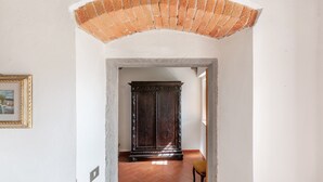 Un arco de entrada que da a un cuarto con piso de baldosas y un armario de madera oscura.