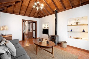 A living room with a sofa, a wooden coffee table, a fireplace, and a TV mounted on the wall.