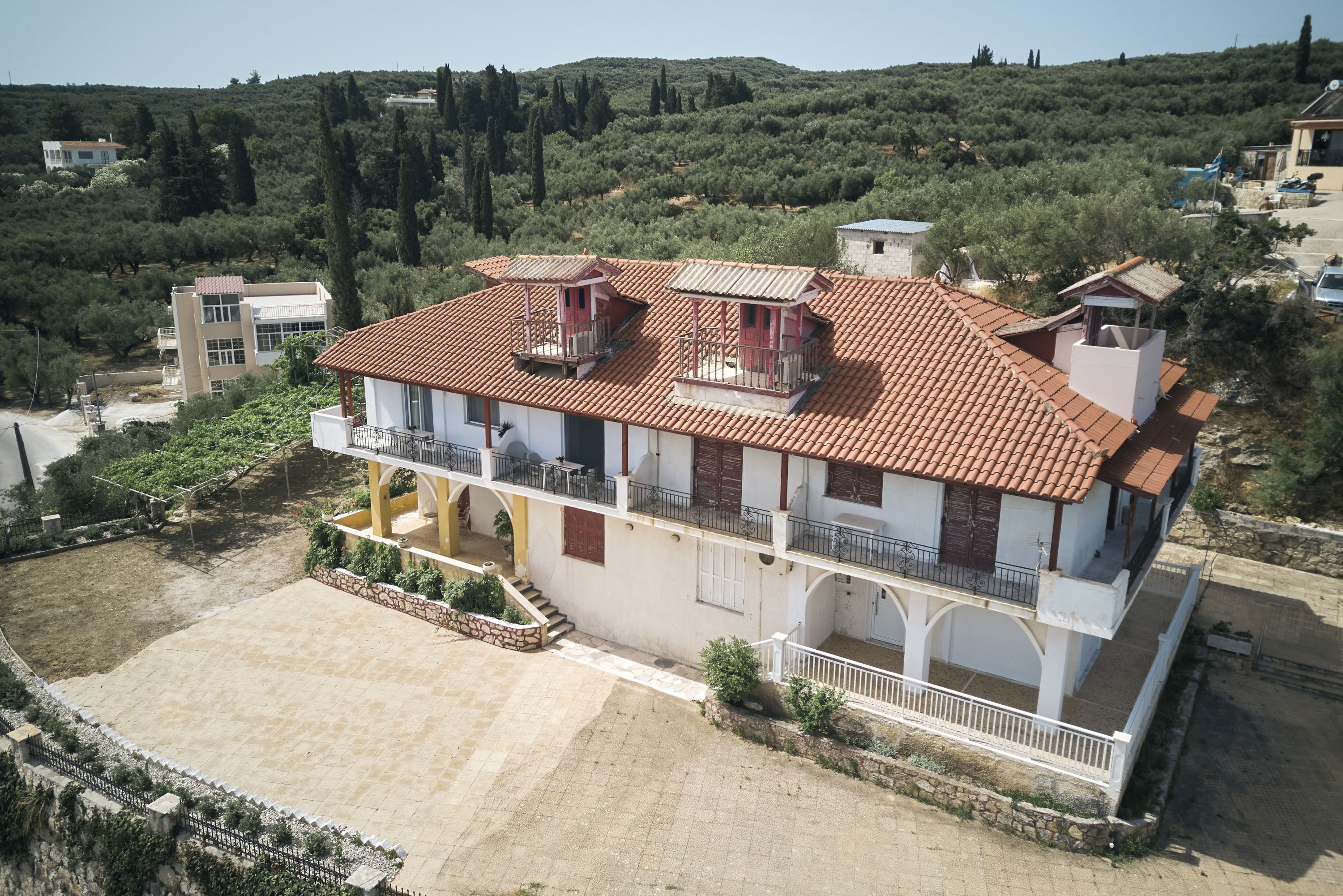 A two-story building with a red-tiled roof, multiple balconies, and a courtyard.