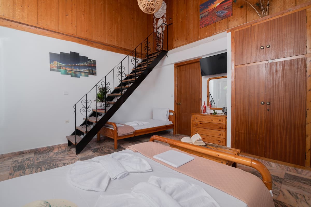 A bedroom with a wooden staircase, a bed with white linens, a wooden dresser, and a wardrobe.