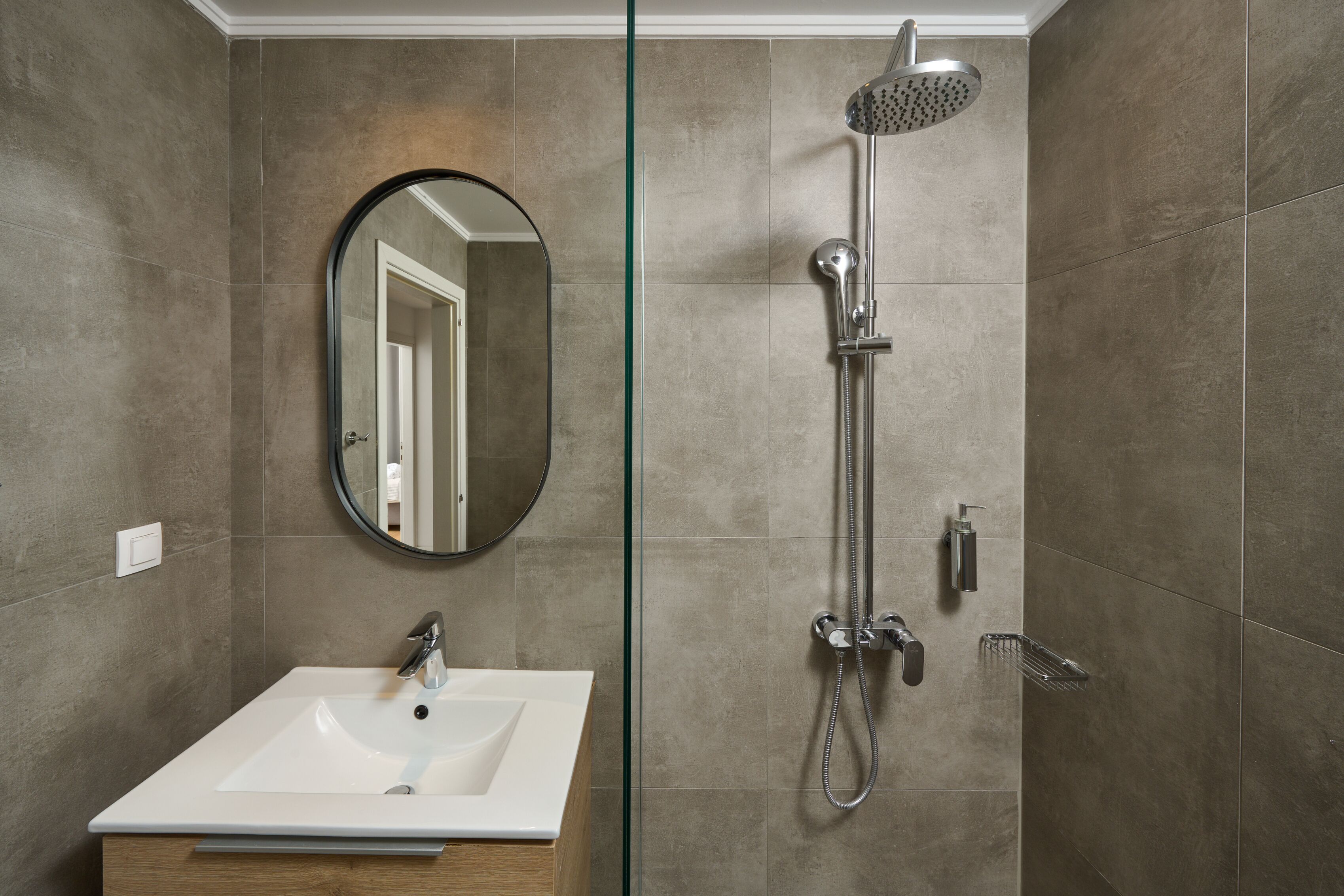 A modern bathroom with a rectangular sink, a handheld showerhead, and a wall-mounted mirror.