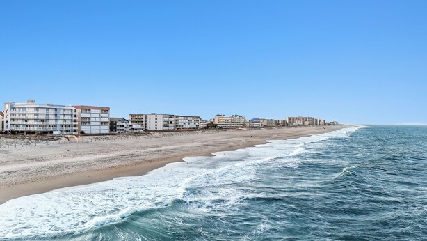 Ein Hotel direkt am Strand mit mehreren Etagen, einem Sandstrand und dem Meer.
