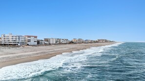 Un hôtel en bord de mer, avec plusieurs étages, une plage de sable et l’océan.