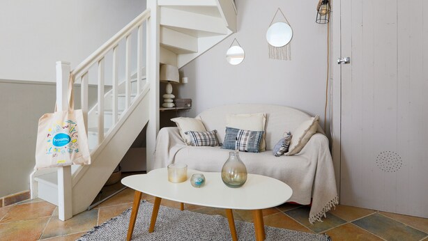 A staircase with a white railing, a beige sofa with patterned cushions, a white coffee table with candles, and a hanging light fixture. - House for 2 adults & 2 kids, central Ars-en-Ré (Ars-en-Ré)