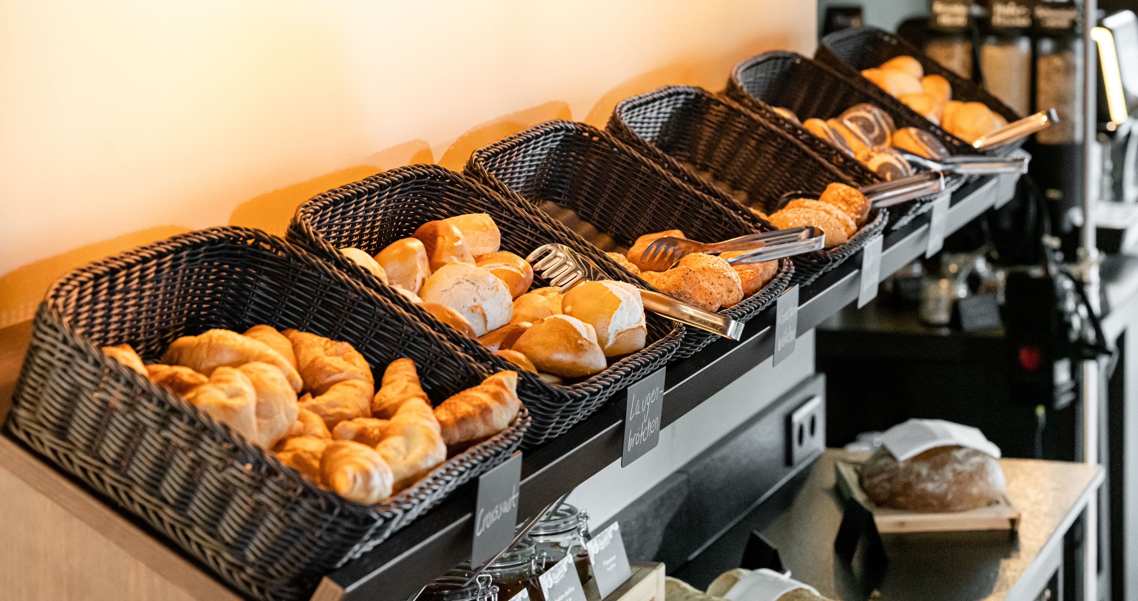 Een buffet met verschillende broden en gebak in rieten manden.