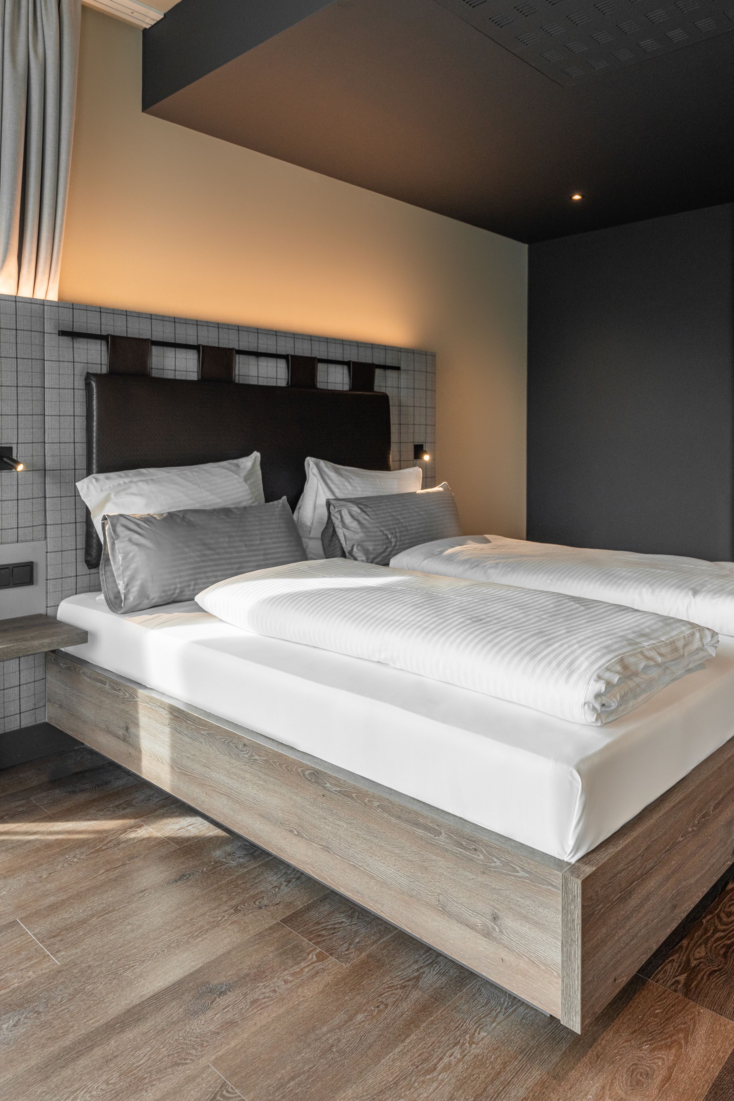 Un dormitorio moderno con una cama grande, cabecera de madera y pared de azulejos.