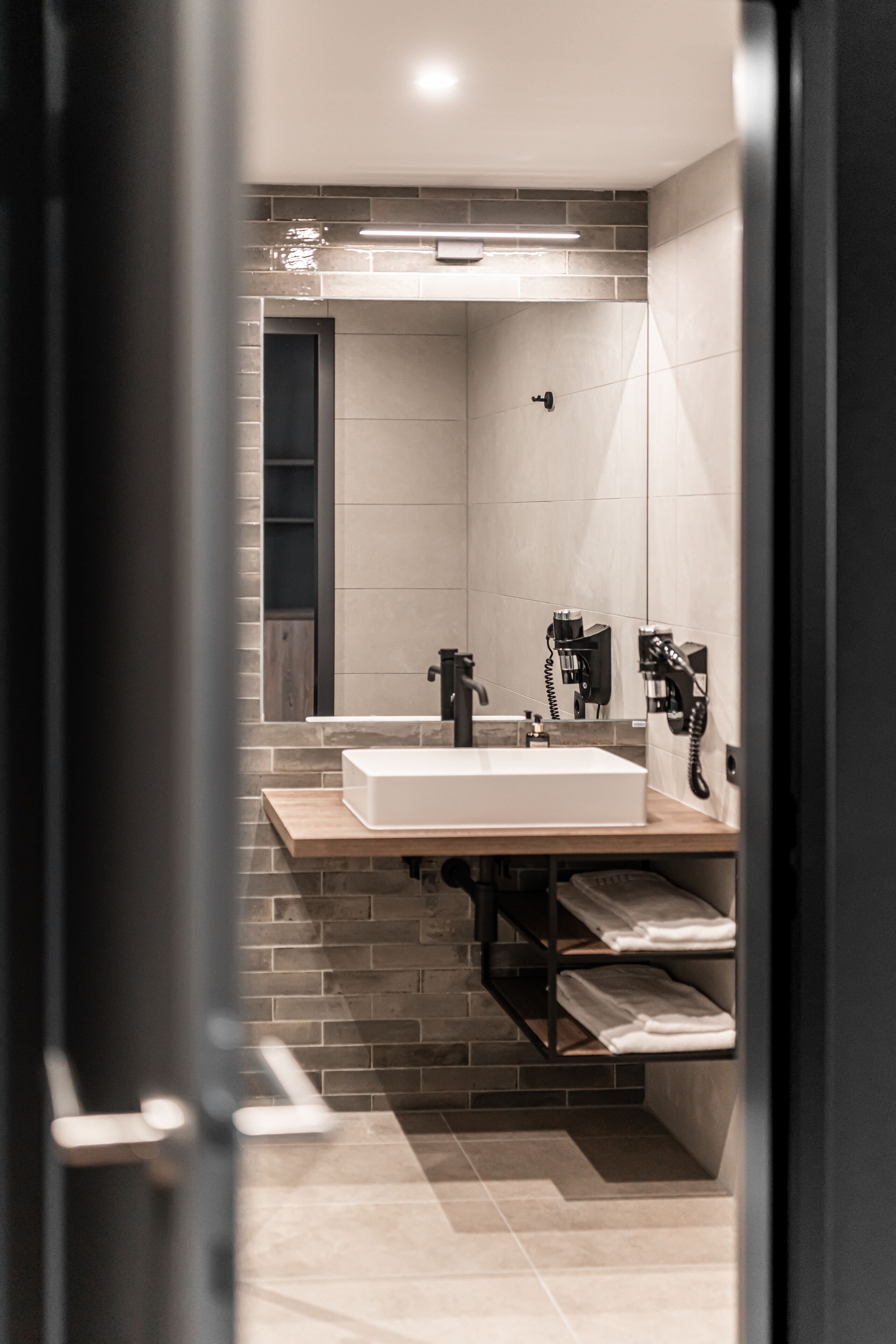 Un baño moderno con un espejo grande, un lavabo y un perchero para toallas.