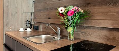 A modern kitchen with a wooden countertop, stainless steel sink, and an induction cooktop.
