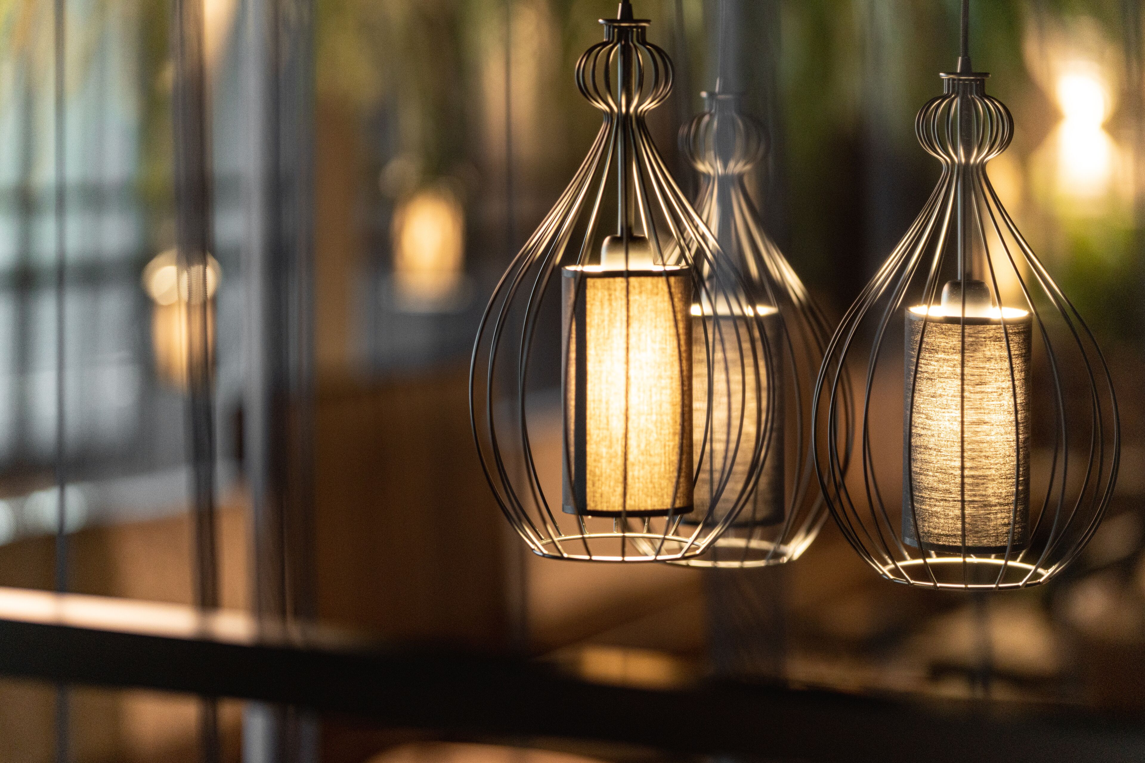 Three hanging pendant lights with a metallic frame and a textured glass cover.
