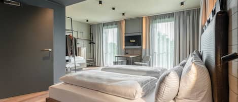 A modern hotel room with a large bed, a desk, and a TV.
