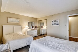 Een hotelkamer met twee bedden, een dressoir, een spiegel en twee ingekaderde foto's aan de muur.