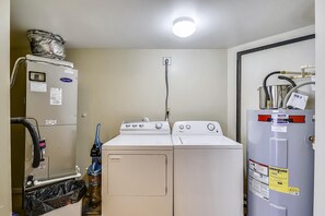 Une buanderie équipée d’un lave-linge et d’un sèche-linge, d’un chauffe-eau et d’un compteur d’eau.