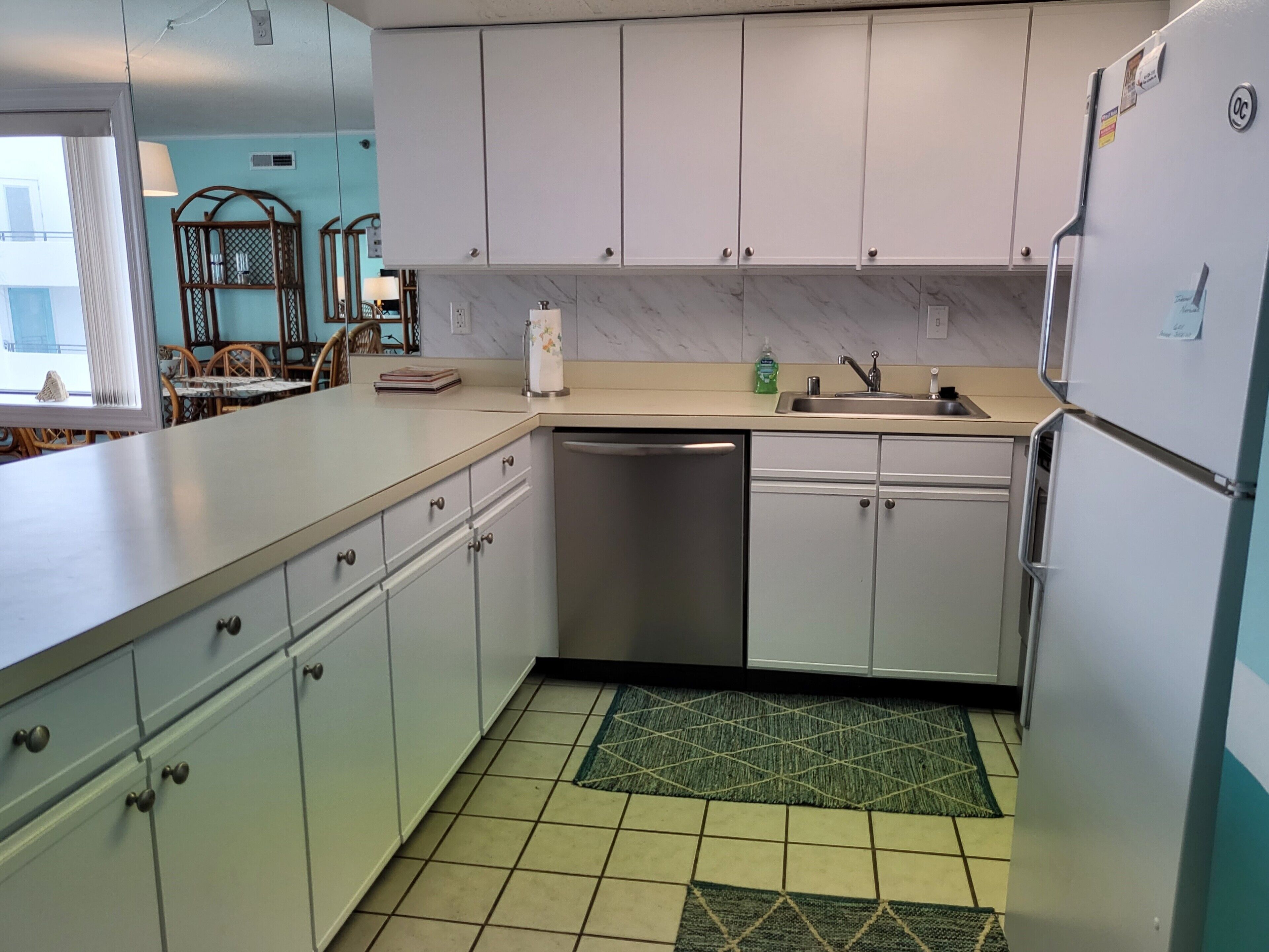 A kitchen with white cabinets, a dishwasher, a sink, and a refrigerator.