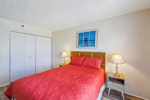 A bedroom with a bed, two bedside lamps, a wooden headboard, a window with a view of the sea, and a wardrobe. - XPLORIE ACTIVITIES & LINENS INCLUDED*! Plaza 3BR/2BA END UNIT with oceanfront & bayside balconies! (Ocean City)