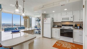 A modern kitchen with white cabinets, a built-in microwave, and a large island with seating. - XPLORIE ACTIVITIES & LINENS INCLUDED*!  OCEAN & BAY VIEWS!! 2BR Capri Condo on 110th Street. (Ocean City)