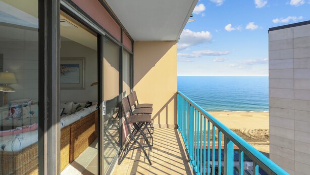 A balcony with a view of the sea, a sofa, and two chairs. - XPLORIE ACTIVITIES & LINENS INCLUDED*!  OCEAN & BAY VIEWS!! 2BR Capri Condo on 110th Street. (Ocean City)