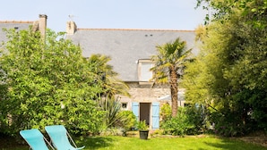 Une maison avec un jardin, une porte bleue et un petit abri de jardin.