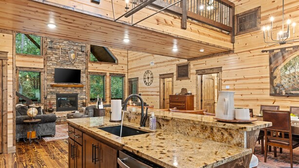 A spacious cabin interior with a kitchen, dining area, and a fireplace.