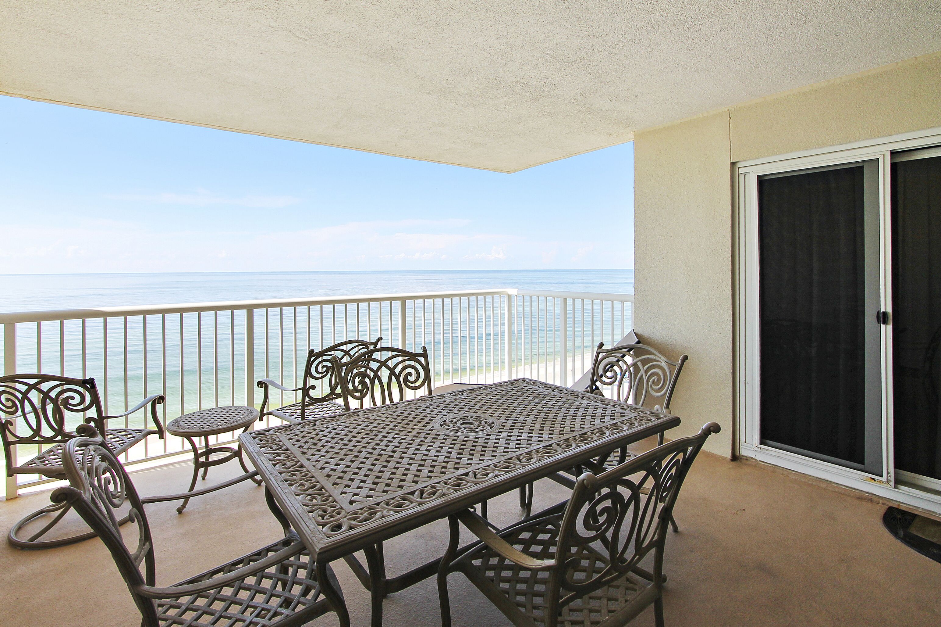 Ein Balkon mit Tisch und Stühlen mit Blick auf das Meer.