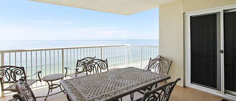 A balcony with a table and chairs, overlooking the sea.
