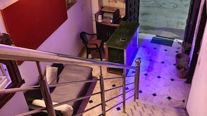 A staircase with metal railings leading to a room with a desk, chair, and a small garden area outside. - The Rustic Monk (Udaipur)