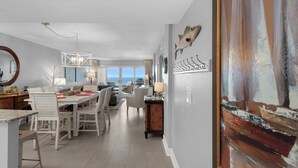 A spacious dining area with a high ceiling and a view of the sea through large windows.