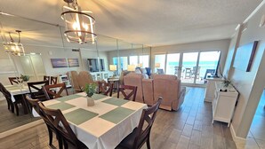 A spacious dining area with a large table, chairs, and a view of the outdoors. - Sandy Key 438: 3 BR/2 BA Beachfront Condo, Perdido Key, FL. On-Site Rental Office, Sleeps 8 (Pensacola)