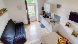 A compact living space with a kitchenette, a sofa, a dining table, and a TV. - Gite Le Mistral 2/4 persons 6kms from the puy du fou park (Mallièvre)