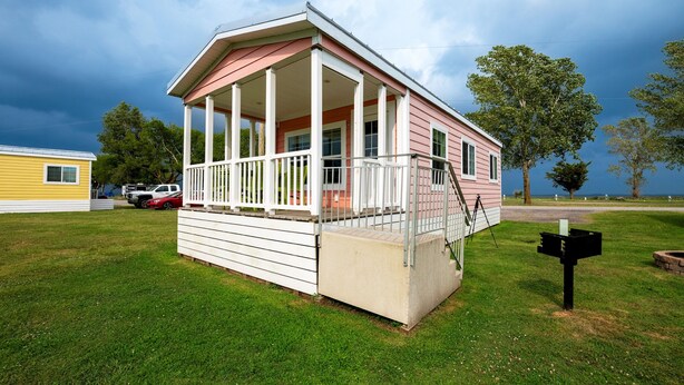 A single-story house with a porch, a small deck, and a mailbox. - Pet-Friendly Cottage in Amenity-Filled Currituck Sound Campground (J04) (Coinjock)