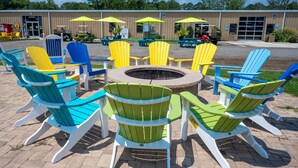 A circular outdoor seating area with colorful Adirondack chairs and a central fire pit. - Pet-Friendly Cottage in Amenity-Filled Currituck Sound Campground (J04) (Coinjock)