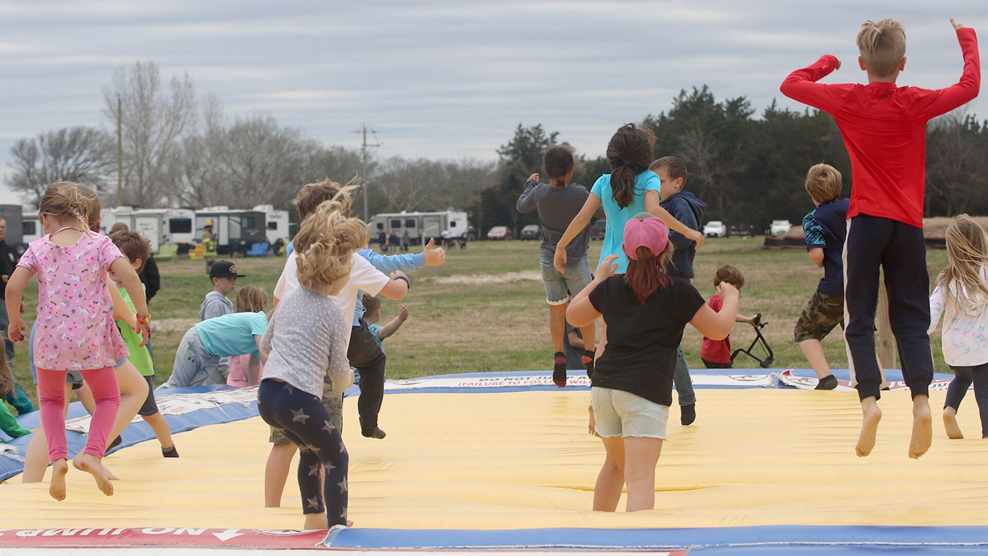 Un groupe d’enfants qui sautent sur un trampoline dans un cadre extérieur.