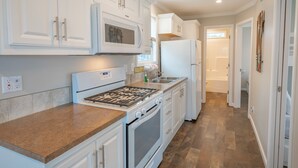 A kitchen with white cabinets, a stainless steel range, a microwave, and a refrigerator. - Waterview Cabin on Currituck Sound - Great Campground Amenities (WV90) (Coinjock)
