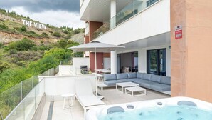 A modern outdoor living area with a hot tub, seating, and a view of a hillside. - La Quinta 3 bedroom apartment with Private Hot Tub (Benahavís)