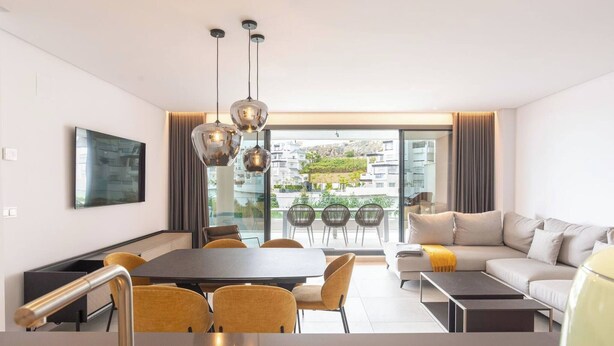 A modern living room with a dining area, large windows, and a view of the city. - La Quinta 3 bedroom apartment with Private Hot Tub (Benahavís)