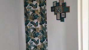 A hallway with a patterned curtain, a ceiling light, and a wall-mounted art piece. - Charming house on the banks of the Louet (Mûrs-Erigné)